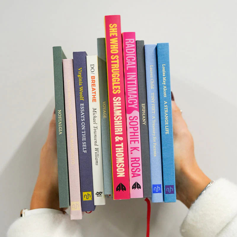 A set of feminist books help between a woman's two hands.